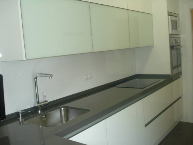 Cocina moderna con encimera continua y mobiliario minimalista reformada por ABC Decoración y Reformas.