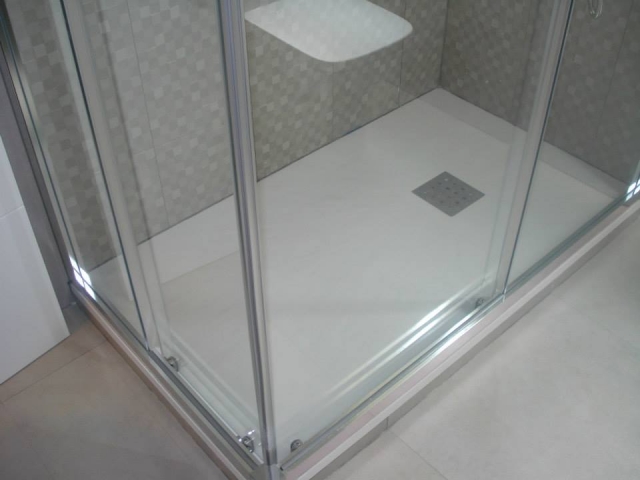 Ducha amplia con mampara transparente y pared cerámica instalada por ABC Decoración y Reformas.